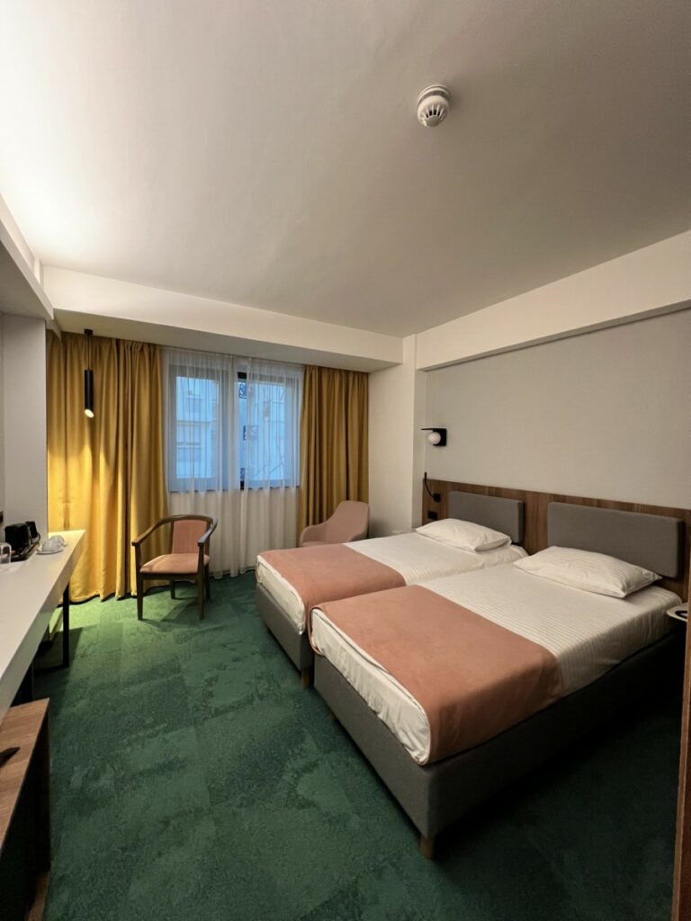 Hotellrom med grønt teppe og to senger