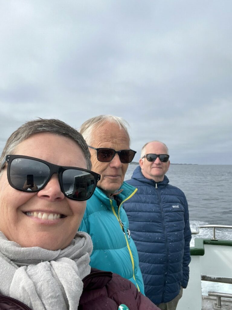 Tre personer på et båtdekk med solbriller